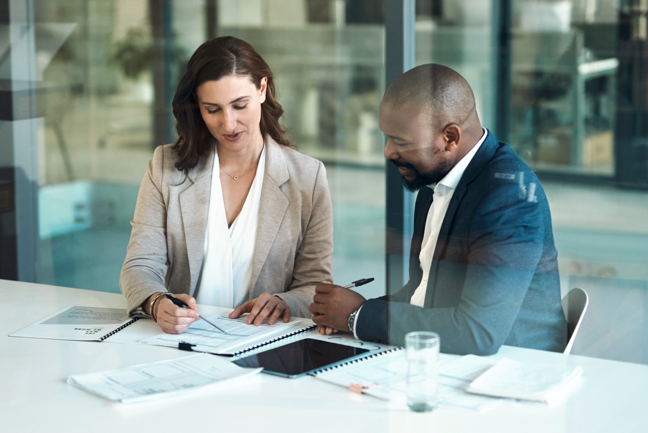 A saleswoman attentively takes a sales prospect through a questionnaire, demonstrating the practice of understanding customer needs through 'why' questions.