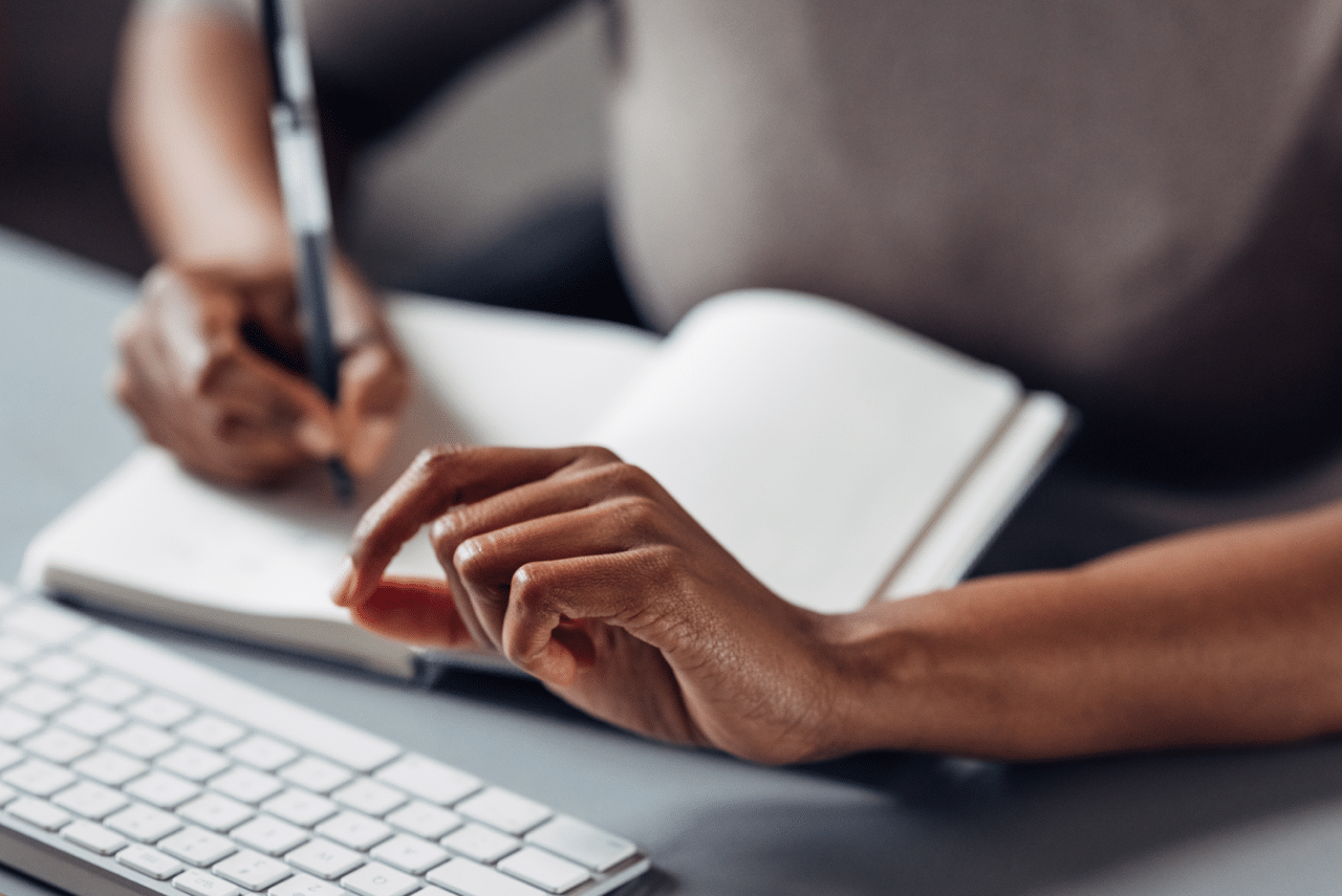 A close-up of a focused salesperson making notes in their meeting agenda, a key part of a sales strategy for maintaining control during client meetings.