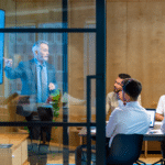 A salesperson delivers a presentation to a group of business people, utilizing effective presentations and marketing materials, as seen on the screen, to communicate key points in an office setting.